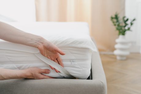 Woman putting on mattress cover.